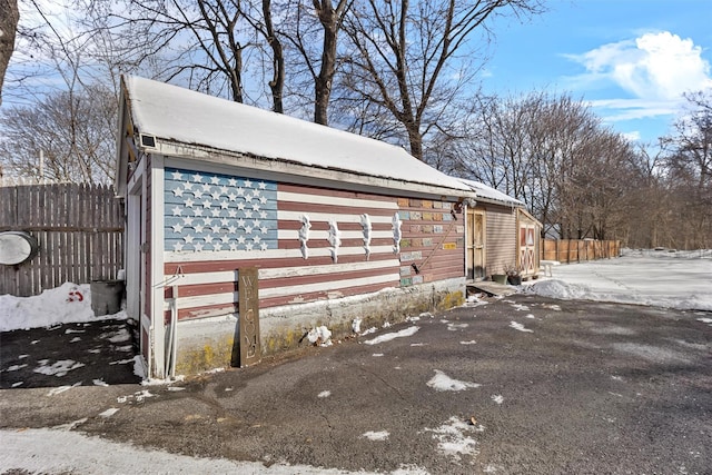 view of snowy exterior featuring a garage and an outdoor structure