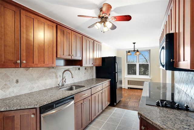 kitchen featuring light stone countertops, radiator, black appliances, backsplash, and sink