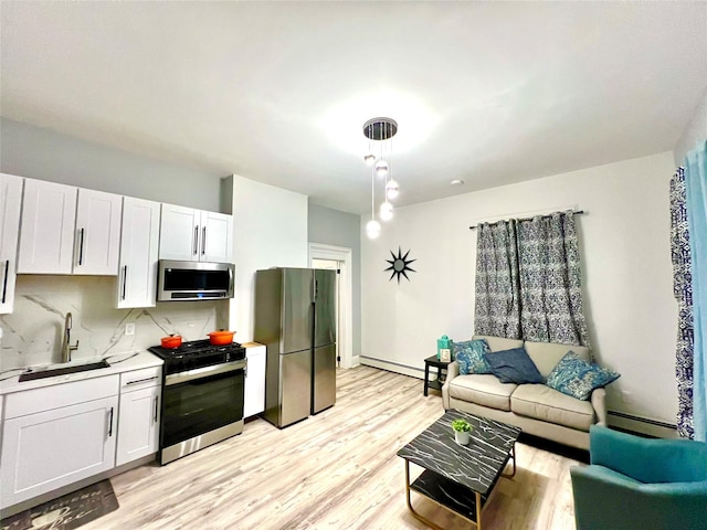 kitchen with tasteful backsplash, white cabinetry, sink, hanging light fixtures, and stainless steel appliances