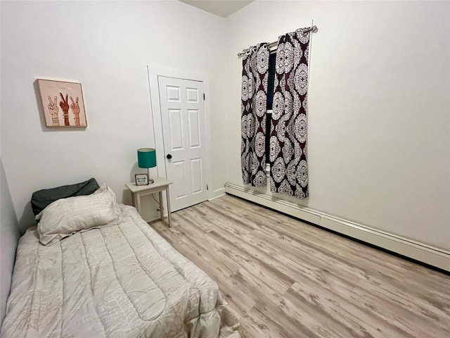 bedroom featuring a baseboard heating unit and light hardwood / wood-style floors