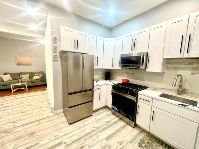 kitchen featuring light wood-type flooring, appliances with stainless steel finishes, sink, and white cabinets