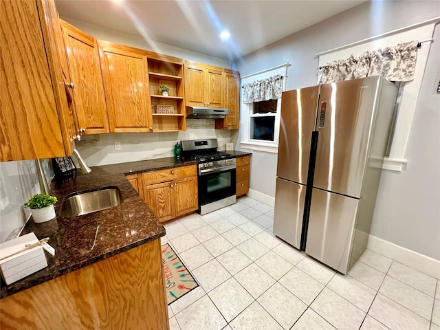 kitchen featuring dark stone countertops, appliances with stainless steel finishes, sink, and light tile patterned floors