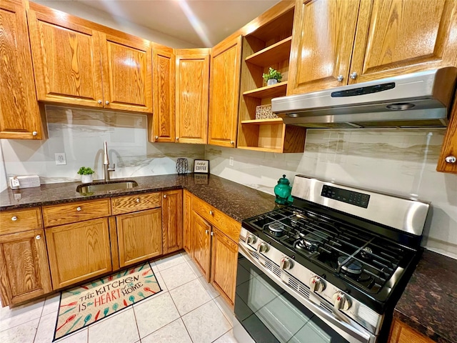 kitchen with light tile patterned flooring, sink, dark stone counters, and stainless steel gas stove