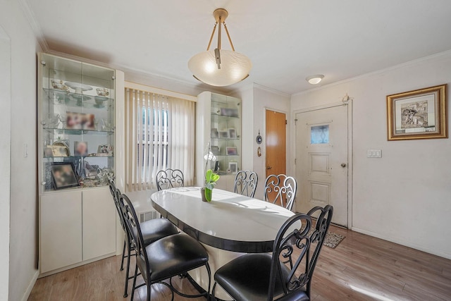 dining space featuring crown molding and light hardwood / wood-style floors