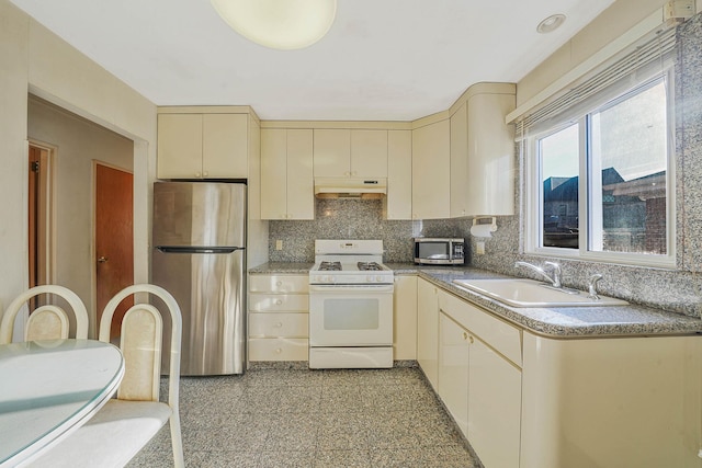 kitchen with backsplash, sink, stainless steel appliances, and cream cabinetry