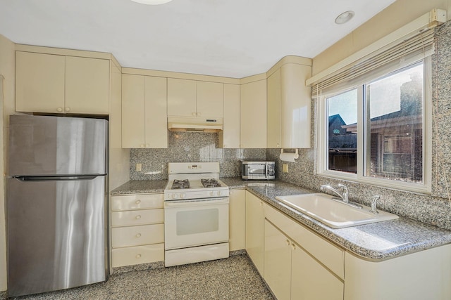 kitchen featuring stainless steel fridge, white range, sink, and cream cabinets