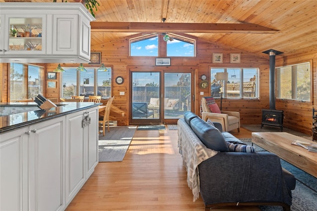 living room with wooden ceiling, a wood stove, light hardwood / wood-style flooring, and vaulted ceiling with beams