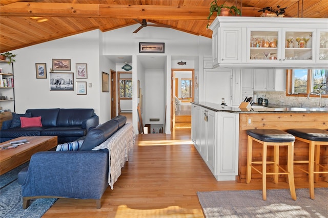 interior space featuring tasteful backsplash, white cabinets, wooden ceiling, and vaulted ceiling with beams