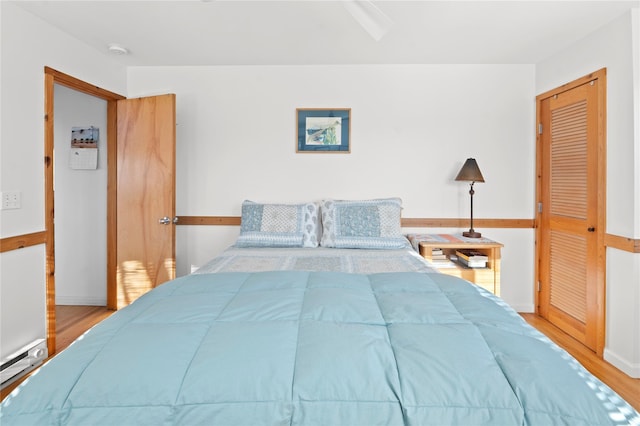 bedroom with light hardwood / wood-style floors and baseboard heating