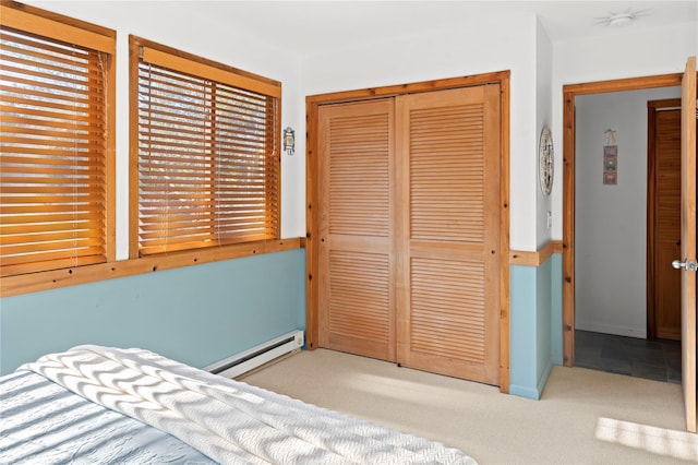 unfurnished bedroom with baseboard heating, light colored carpet, and a closet