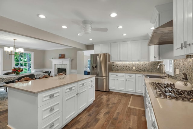 kitchen with stainless steel appliances, white cabinetry, wall chimney exhaust hood, and sink