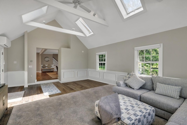 living room featuring an AC wall unit, a wealth of natural light, vaulted ceiling with skylight, and ceiling fan