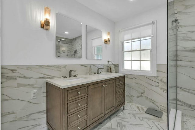 bathroom with tiled shower, vanity, and tile walls