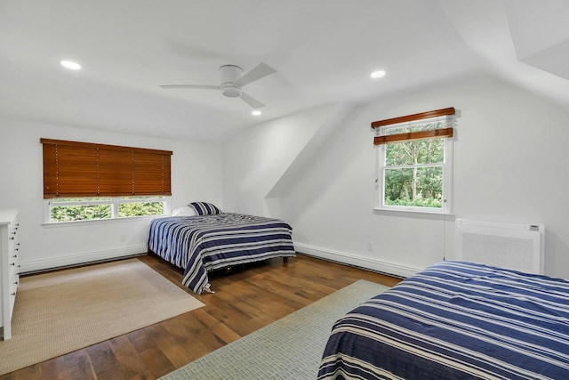 bedroom featuring hardwood / wood-style flooring, ceiling fan, multiple windows, and a baseboard heating unit