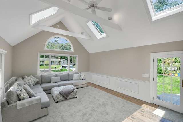 living room with ceiling fan, light wood-type flooring, and a skylight