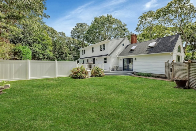 rear view of house featuring a wooden deck and a lawn