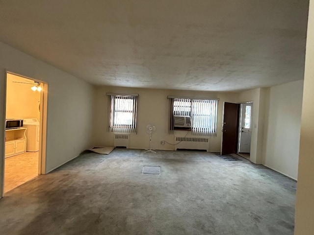 spare room featuring carpet flooring, separate washer and dryer, and radiator