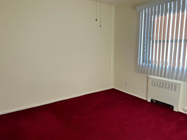 spare room featuring carpet floors and radiator