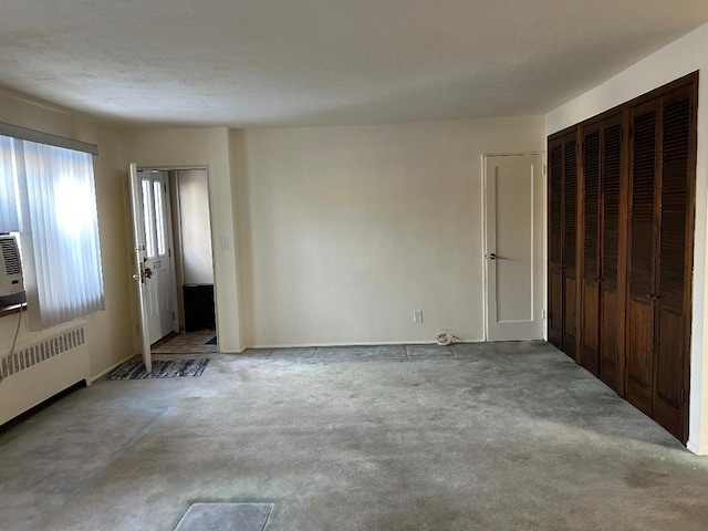 spare room featuring light colored carpet and radiator