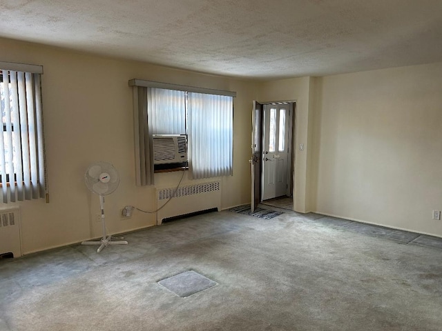 carpeted foyer entrance featuring a textured ceiling, radiator, and cooling unit