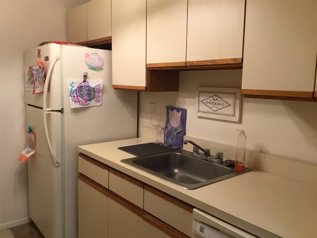 kitchen featuring dishwashing machine, sink, and white cabinets