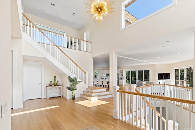 staircase featuring wood-type flooring, a high ceiling, and a chandelier