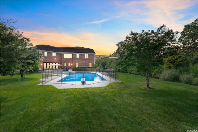 pool at dusk featuring a patio area and a lawn