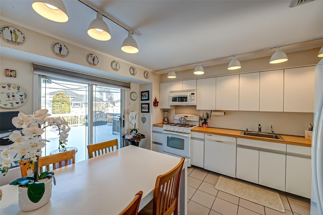 kitchen featuring sink, white appliances, light tile patterned floors, white cabinetry, and decorative light fixtures