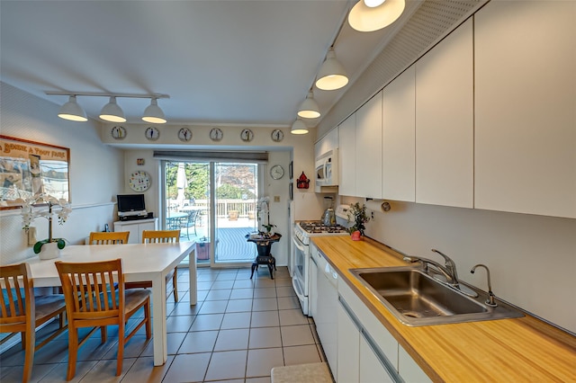 kitchen with white cabinetry, sink, light tile patterned floors, and white appliances