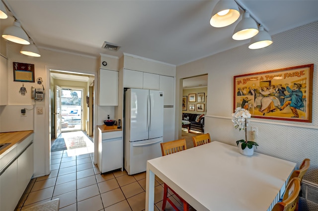 kitchen featuring hanging light fixtures, light tile patterned flooring, white fridge, and white cabinets