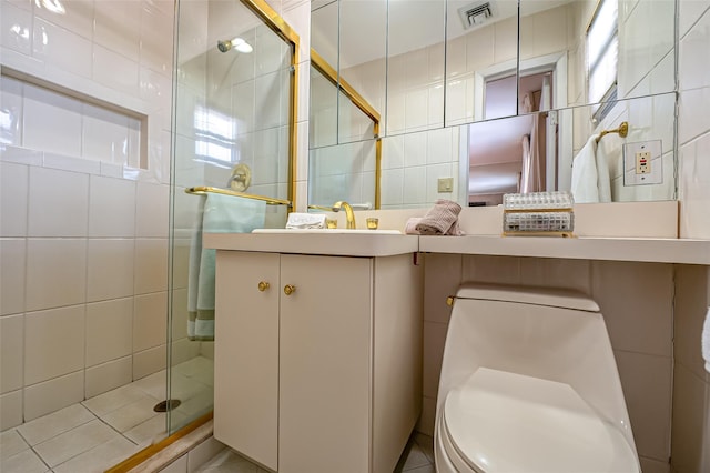 bathroom featuring a shower with door, vanity, tile walls, and toilet