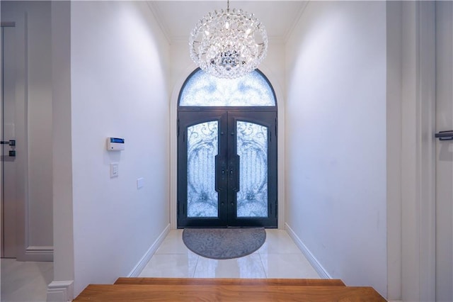 tiled foyer entrance featuring french doors, an inviting chandelier, and ornamental molding