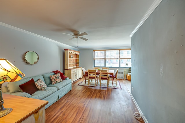 living room featuring radiator, crown molding, wood-type flooring, and ceiling fan