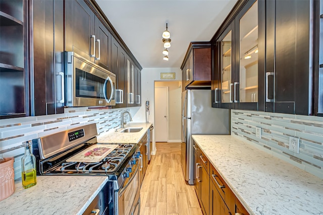 kitchen featuring appliances with stainless steel finishes, tasteful backsplash, sink, light hardwood / wood-style floors, and light stone countertops