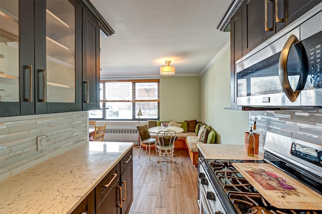 kitchen with light hardwood / wood-style flooring, appliances with stainless steel finishes, light stone countertops, ornamental molding, and decorative backsplash