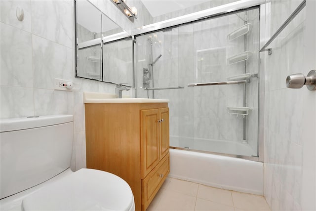 full bathroom with vanity, toilet, bath / shower combo with glass door, and tile walls