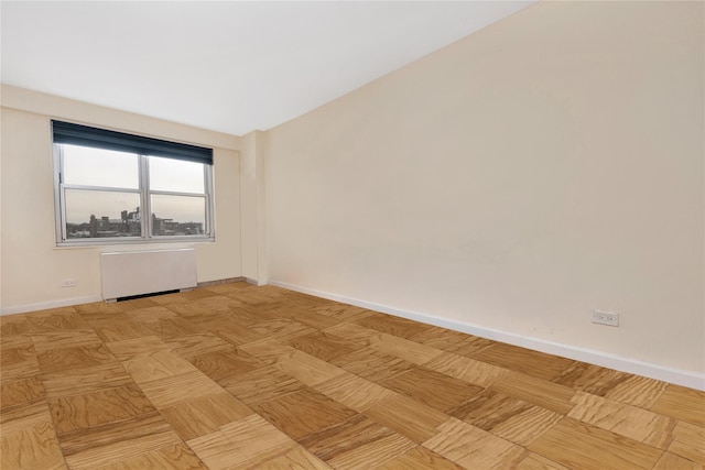 spare room featuring radiator and light parquet flooring