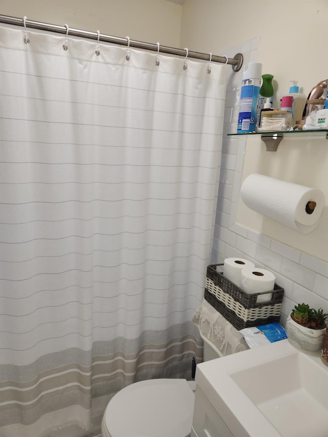 bathroom featuring curtained shower, toilet, and sink