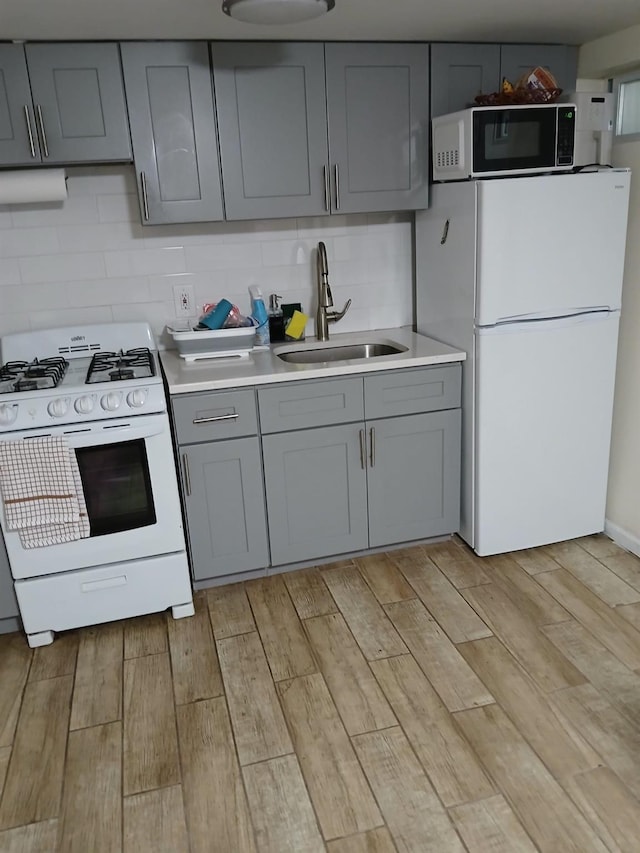 kitchen featuring light wood-type flooring, white appliances, gray cabinets, and sink