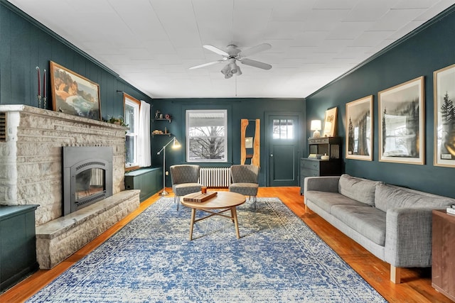 living room featuring hardwood / wood-style flooring, radiator heating unit, crown molding, and a fireplace