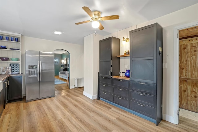 kitchen featuring stainless steel fridge with ice dispenser, ceiling fan, radiator heating unit, and light hardwood / wood-style floors