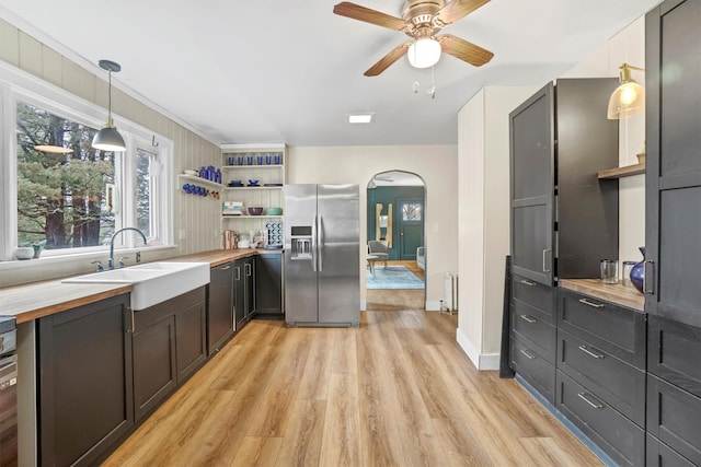 kitchen with hanging light fixtures, sink, light wood-type flooring, stainless steel fridge with ice dispenser, and butcher block counters