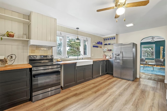 kitchen with light hardwood / wood-style floors, extractor fan, hanging light fixtures, sink, and stainless steel appliances