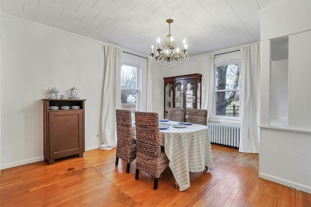 dining area featuring hardwood / wood-style flooring, plenty of natural light, radiator, and a chandelier