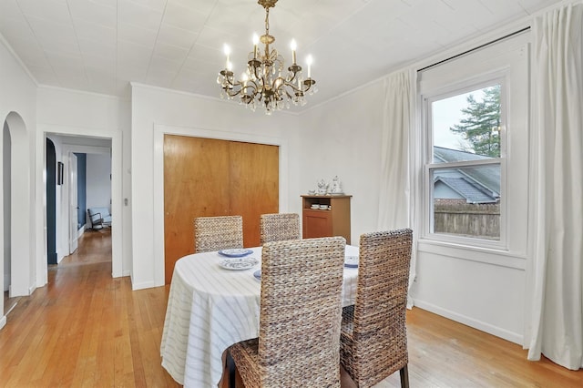 dining space featuring light wood-type flooring, a notable chandelier, and ornamental molding