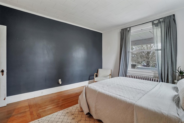 bedroom with radiator heating unit and light hardwood / wood-style flooring