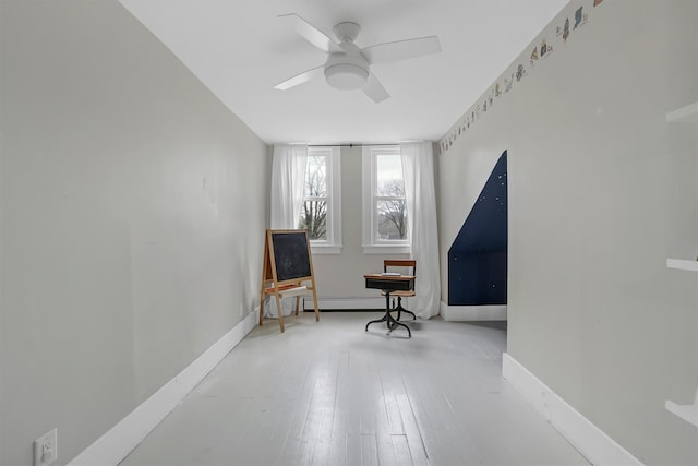 living area with ceiling fan, baseboard heating, and hardwood / wood-style flooring