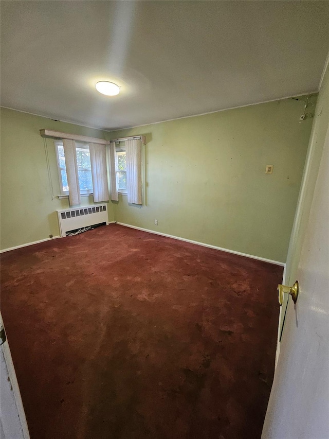 unfurnished room with radiator and carpet floors