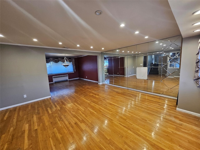 unfurnished living room featuring radiator and hardwood / wood-style flooring