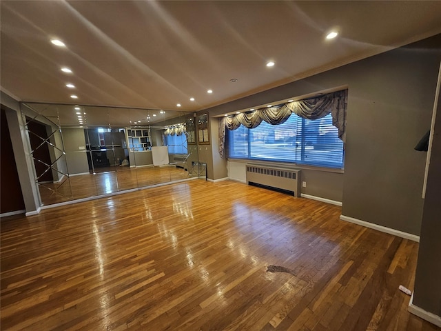 unfurnished living room with radiator heating unit, hardwood / wood-style flooring, and crown molding